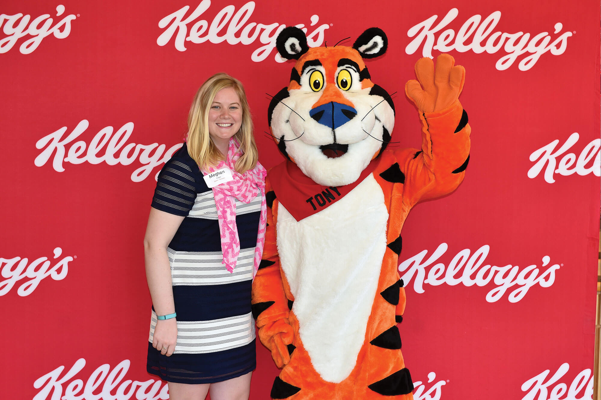 A female student standing with a Tony the Tiger mascot in front of a Kellogg's backdrop