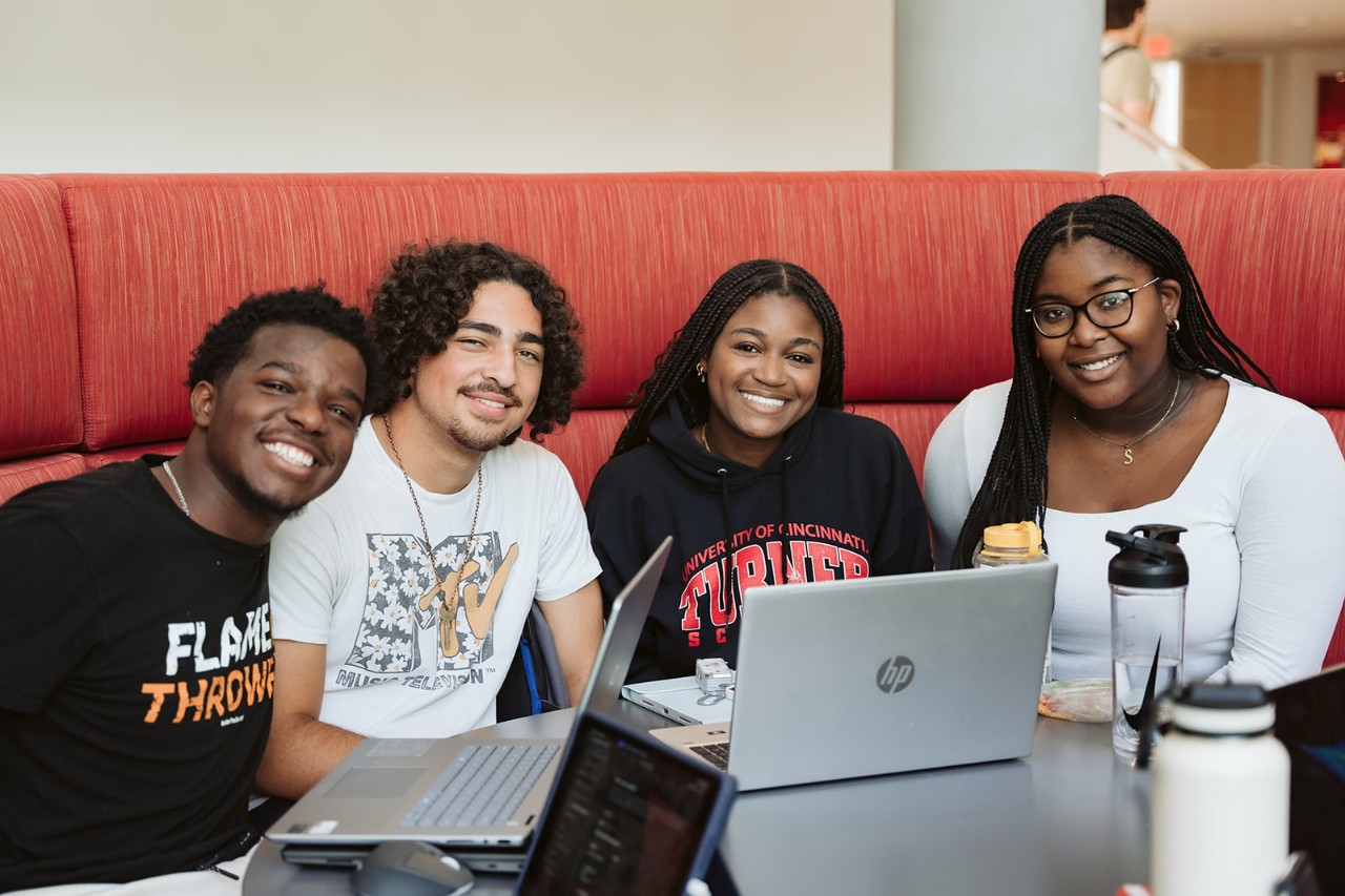 Lindner College of Business students pose on a red couch in a study area