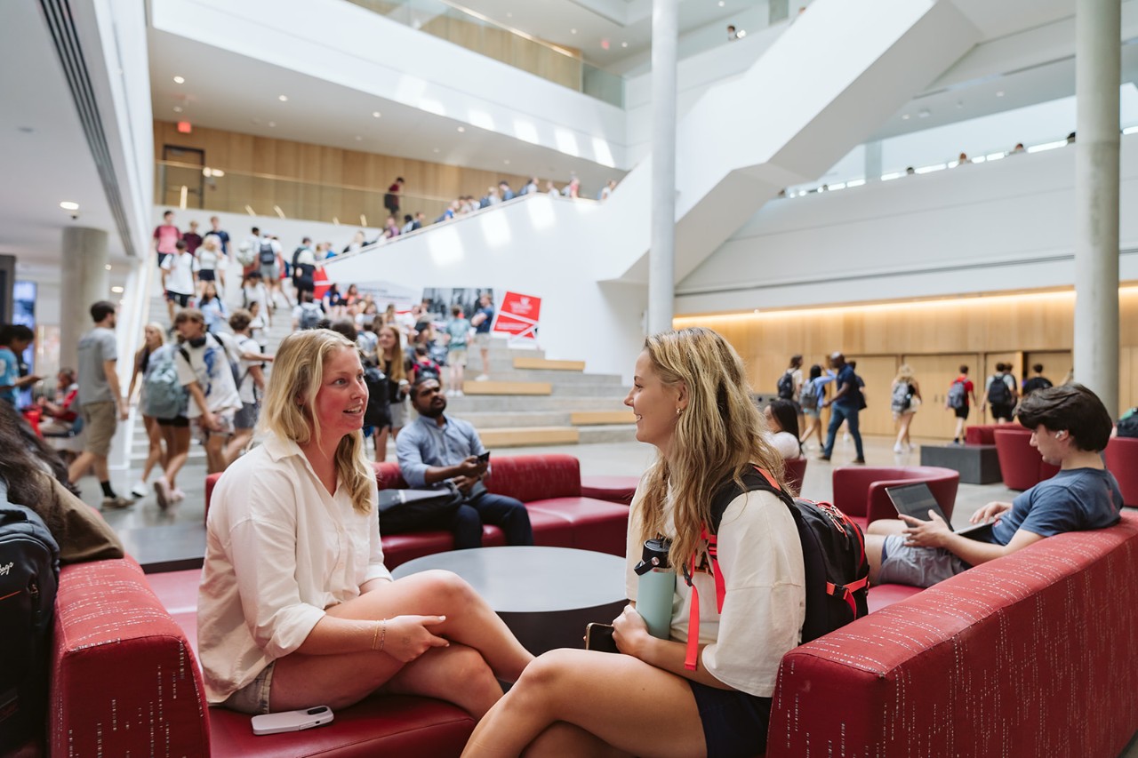 Two University of Cincinnati students share a conversation in a meeting space at the Lindner College of Business